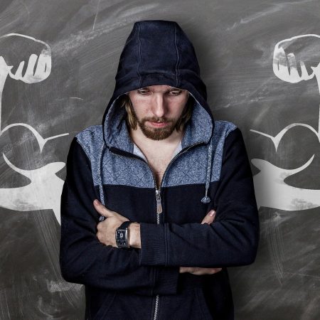 man in hoodie in front of wall with drawn muscles